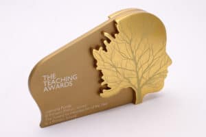 A bespoke gold trophy engraved with a face and growing tree for the National Teaching Awards